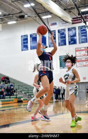 USA. Player finishing off a drive with an uncontested layup while an opponent is left to watch the unfolding action from the floor. Stock Photo