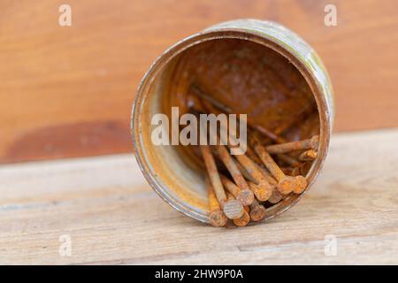 A few rusty nails in a rusty can on a wooden background. Stock Photo