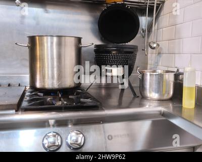 Large pot on the cooker of a restaurant next to oil and an electric fryer Stock Photo
