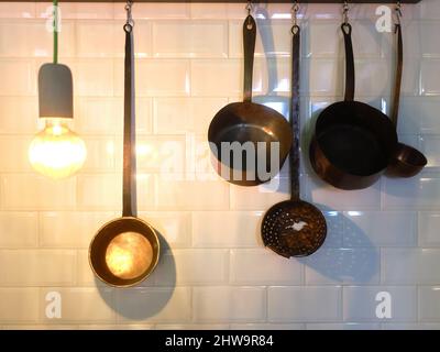 Various kitchen utensils hanging on the wall of a restaurant Stock Photo