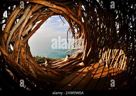 Treebones Twig Hut handmade with woven branches, built by a Big Sur artist, overlooking the vast Pacific Ocean, coastline and Big Sur, California, USA Stock Photo