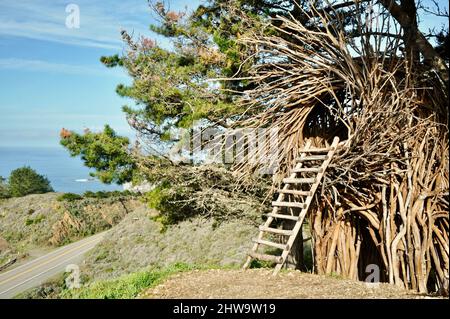 Treebones Twig Hut handmade with woven branches, built by a Big Sur artist, overlooking the vast Pacific Ocean, coastline and Big Sur, California, USA Stock Photo