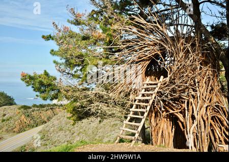 Treebones Twig Hut handmade with woven branches, built by a Big Sur artist, overlooking the vast Pacific Ocean, coastline and Big Sur, California, USA Stock Photo