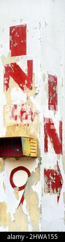 In sign, with arrow is painted on a concrete column.  Column is painted white and lettering is in red.  Paint is cracked, faded and peeling with age. Stock Photo
