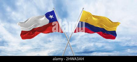 crossed national flags of Chile and Colombia flag waving in wind at cloudy sky. Symbolizing relationship, dialog, travelling between two countries. Co Stock Photo