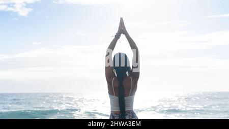 woman in sport clothes practicing yoga and meditating on beach in morning Stock Photo