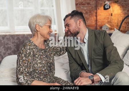 middle-aged caucasian businessman making silly faces and making his elderly grey-haired mother laugh. High quality photo Stock Photo
