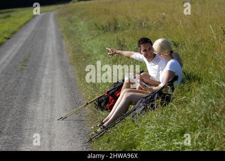 couple sitting by the wayside taking a break, Germany Stock Photo