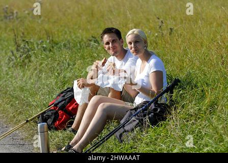 couple sitting by the wayside taking a break, Germany Stock Photo