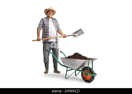 Full length portrait of a mature farmer with a spade and a wheelbarrow full of soil isolated on white background Stock Photo