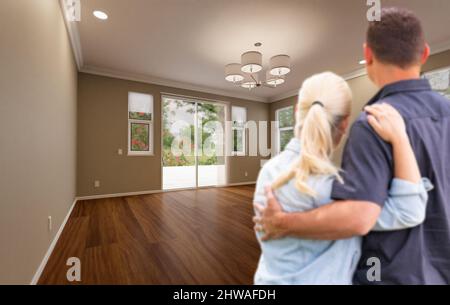 Young Adult Couple Looking At Empty Room of New House. Stock Photo