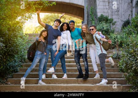 Group of young multiracial students waving at the camera on some stairs Stock Photo