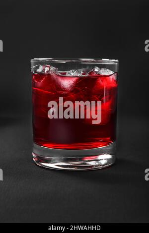 One-color, red transparent cocktail, cold tea in a low glass with ice cubes with the taste of grapefruit, berries, strawberries, cherries. Side view. Stock Photo