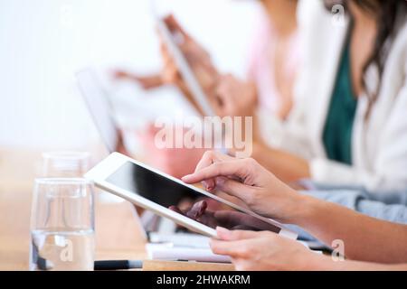Wireless freedom in the boardroom. Cropped shot of a group of businesspeople using their wireless devices during a meeting. Stock Photo