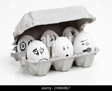 Dont close the lid, were afraid of the dark. Studio shot of faces drawn onto a carton of eggs. Stock Photo