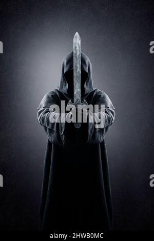 Warrior with hooded cape and medieval sword over dark misty background Stock Photo
