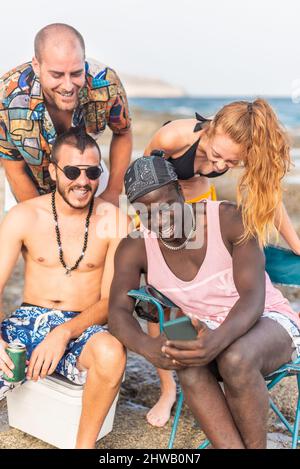 four multiracial friends having a good time at the beach Stock Photo