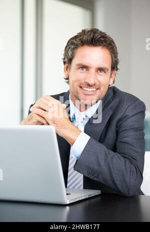 Smiling business man using laptop. Portrait of business man using laptop and giving you a warm smile. Stock Photo