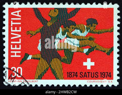 SWITZERLAND - CIRCA 1974: A stamp printed in Switzerland shows Gymnast and hurdlers, circa 1974. Stock Photo