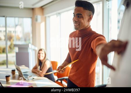 A young male lecturer is giving an explanation about a content on the board during a business lecture in a pleasant atmosphere in the conference room. Stock Photo