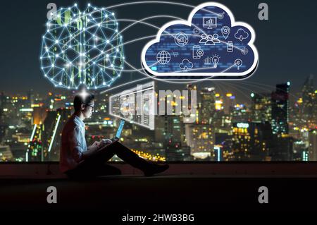 Asian businessman sitting and using the laptop and working with brain and virtual screen connecting with cloud technology over the cityscape backgroun Stock Photo