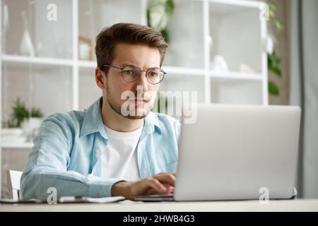 An attractive young man is working on a laptop. Stock Photo