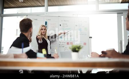 Engaging the team in new ideas. Shot of a businesswoman giving a presentation to her colleagues on a whiteboard in a boardroom. Stock Photo
