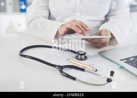 Digital tablets are recommended by doctors. Cropped shot of an unrecognizable female doctor using a digital tablet while working in her office. Stock Photo