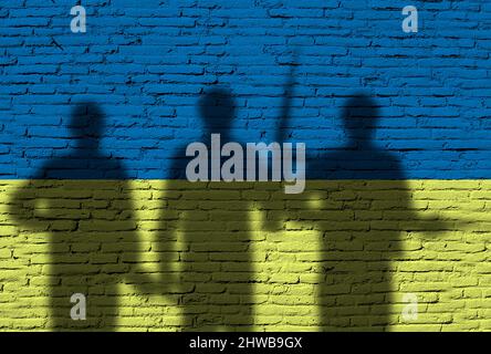 Flag of Ukraine painted on a brick wall with soldiers. War between Ukraine and Russia Stock Photo