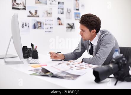 Making his final selection. A photographer looking at his images in his office. Stock Photo