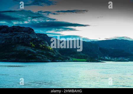 Herbst bei Tonnes, Nordland, Norwegen. Norwegische Küste mit gelben Lärchen am Berghang und einem kleinen Dorf. Morgenlicht trotz Wolken am Himmel Stock Photo