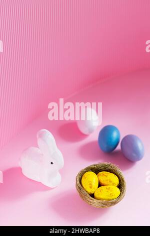 Easter eggs and rabbit on a pink background. Multicolored eggs for Easter celebration. Copy space Stock Photo