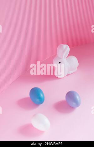 Easter eggs and rabbit on a pink background. Multicolored eggs for Easter celebration. Copy space Stock Photo