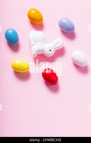 Easter eggs and white bunny. Easter decorations on a pink pastel background. Top view Stock Photo