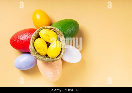 Multicolored easter eggs on a beige background. Painted eggs in a natural nest. Happy Easter concept. Top view. Copy space Stock Photo