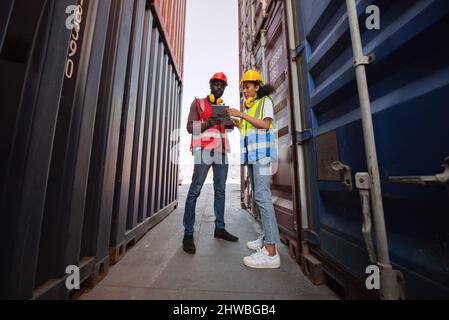 Two African american male and female worker using tablet and checking control loading freight containers from Cargo freight ship for import export. Stock Photo