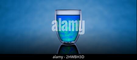 Double-walled insulated glass beaker, filled with blue and green liquid and round ice.Bright reflective background Stock Photo