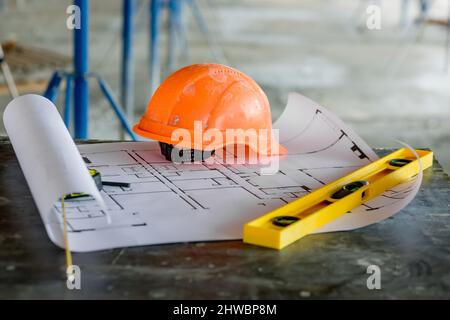 Blueprints project building, construction level and helmet, close up. Construction concept. Stock Photo