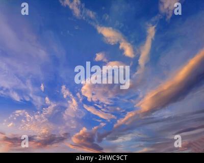 Beautiful pink and golden clouds in blue sky at sunset. Peaceful sky above Stock Photo