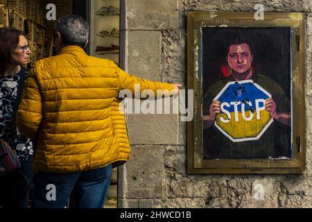 Barcelona, Spain. 5th Mar, 2022. Commuters look at a graffiti by Italian urban artist 'TVBoy', Salvatore Benintende, titled 'Stop The Madness' depicting Ukrainian president Volodymyr Zelensky holding a Stop sign in the national colors in protest to the ongoing Russian attacks Credit: Matthias Oesterle/Alamy Live News Stock Photo