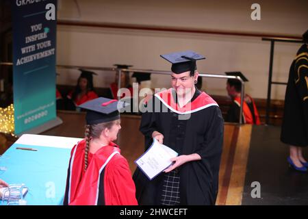 An European Graduate receives their degree at their graduation day ceremony. This formal event where graduands (before) change into graduates (after) Stock Photo