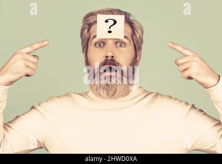 Beard man question mark in head, solution problems. Thinking man with question mark on blue background. Man with question mark on forehead looking up Stock Photo