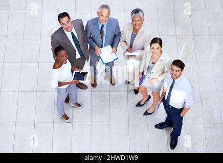 They know what theyre doing. Portrait of a group of businesspeople holding paperwork and their digital devices. Stock Photo