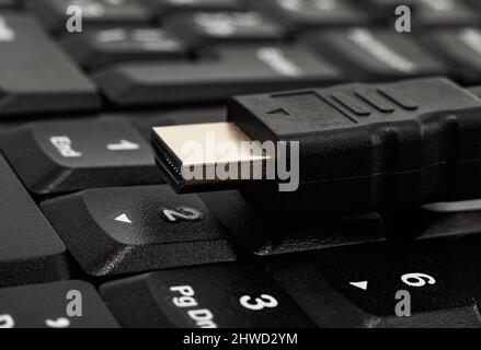 hdmi cable lies on a wireless keyboard close-up. TV connection cable Stock Photo