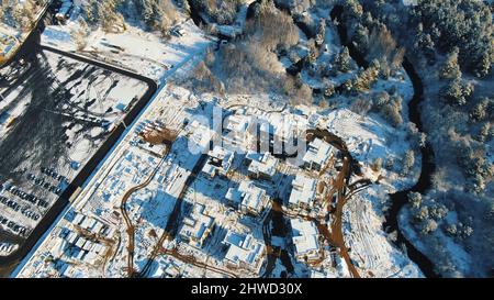 Sports and recreation concept. Aerial view of the winter cottages construction on the modern ski resort surrounded by forest. Stock Photo