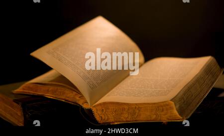 Pages of old book are turned over on isolated background. Stock footage. Ancient book with old yellow pages and patterns flipping over dark background Stock Photo