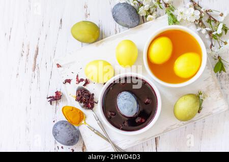 Natural dye for easter eggs, celebration Easter. Homemade colored easter eggs in carcade and turmeric on a rustic table. Top view flat lay. Copy space Stock Photo