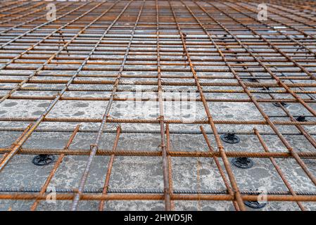 The foundation slab is made of reinforcement rods, bound with tie wire, bonded reinforcement visible up close. Stock Photo