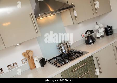 Pans stacked on gas cooker hob in kitchen of modern showhome, fitted kitchen units, floor and wall cupboards Stock Photo