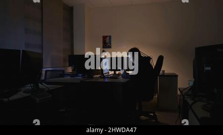 Young worker is sitting on phone in office. Stock footage. Employee sat up late in office at computer and sits in smartphone wasting time. Stock Photo